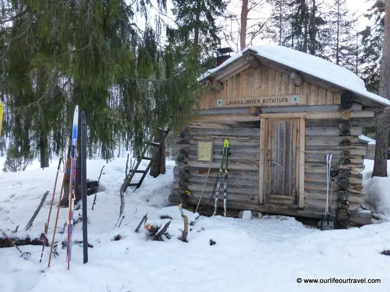 An open wilderness hut approached by skis during the winter in Finland.